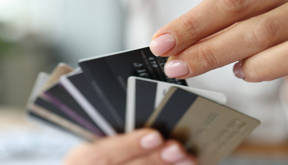 Fan of plastic credit cards is in woman's hand.